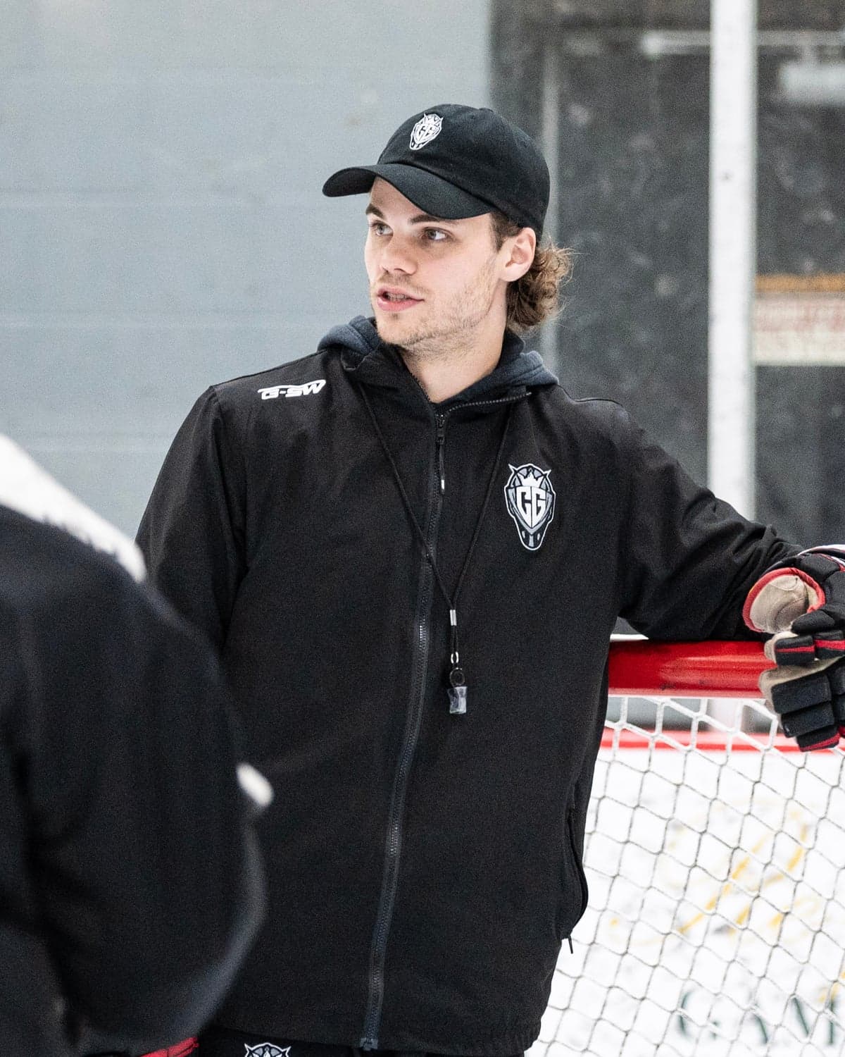 Cam Gray coaching goaltenders at the net, in a CGG cap and jacket.