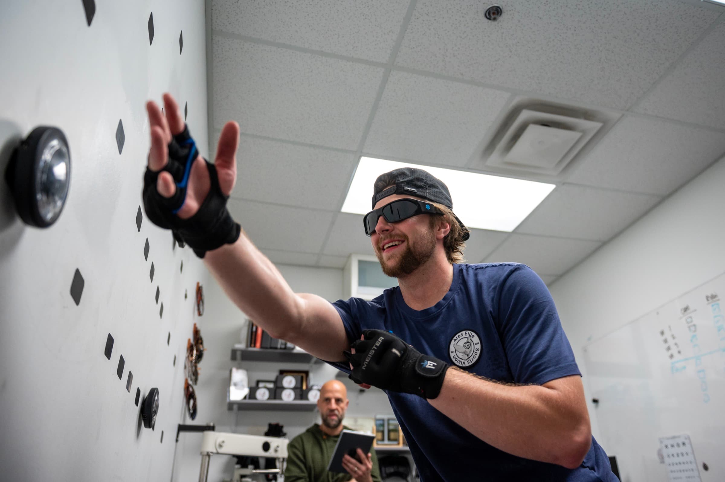 A goalie training reaction and tracking on the AESV wall while a trainer records the session