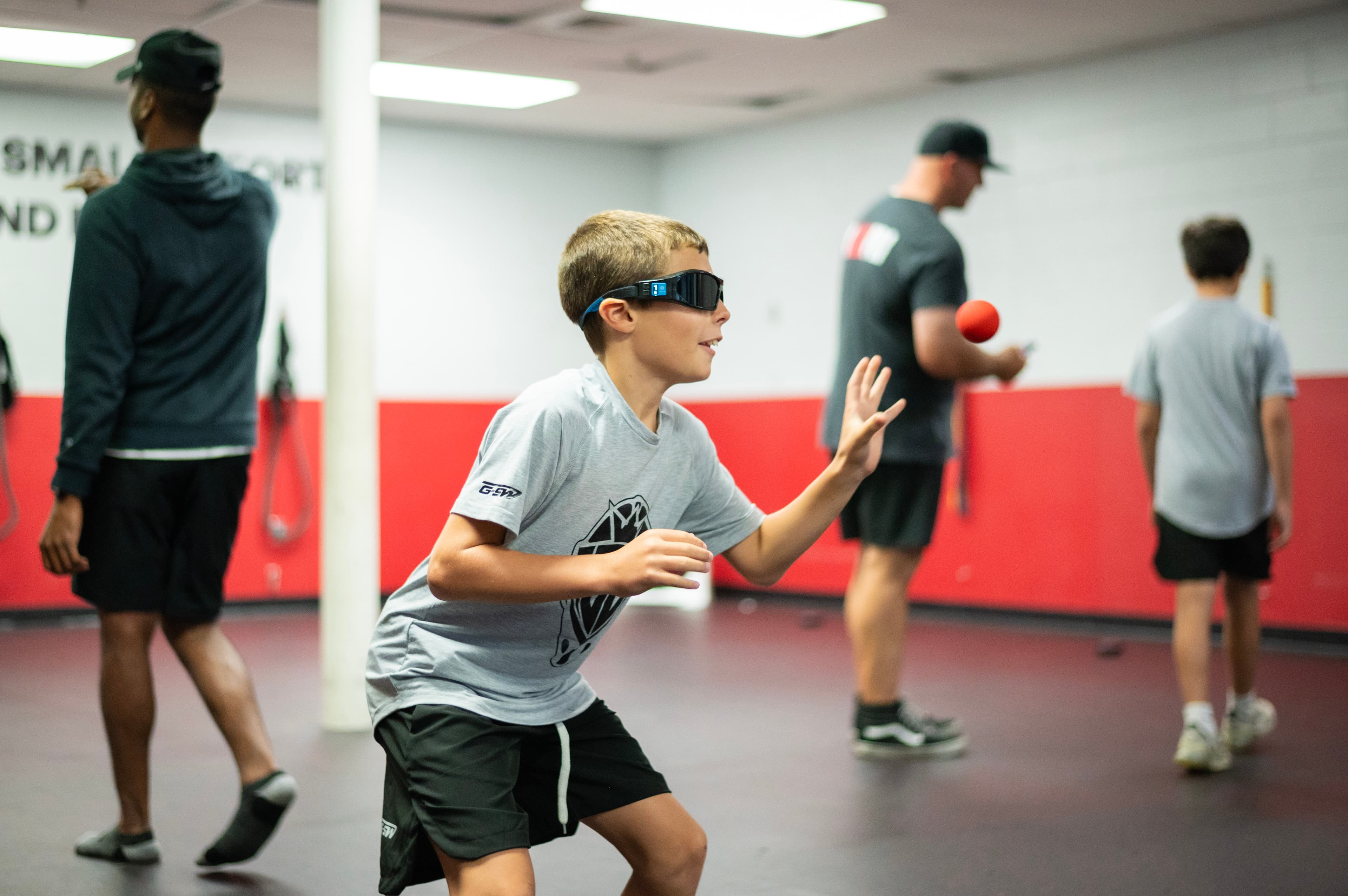 A goalie in vision goggles catching a reaction ball off the ice.