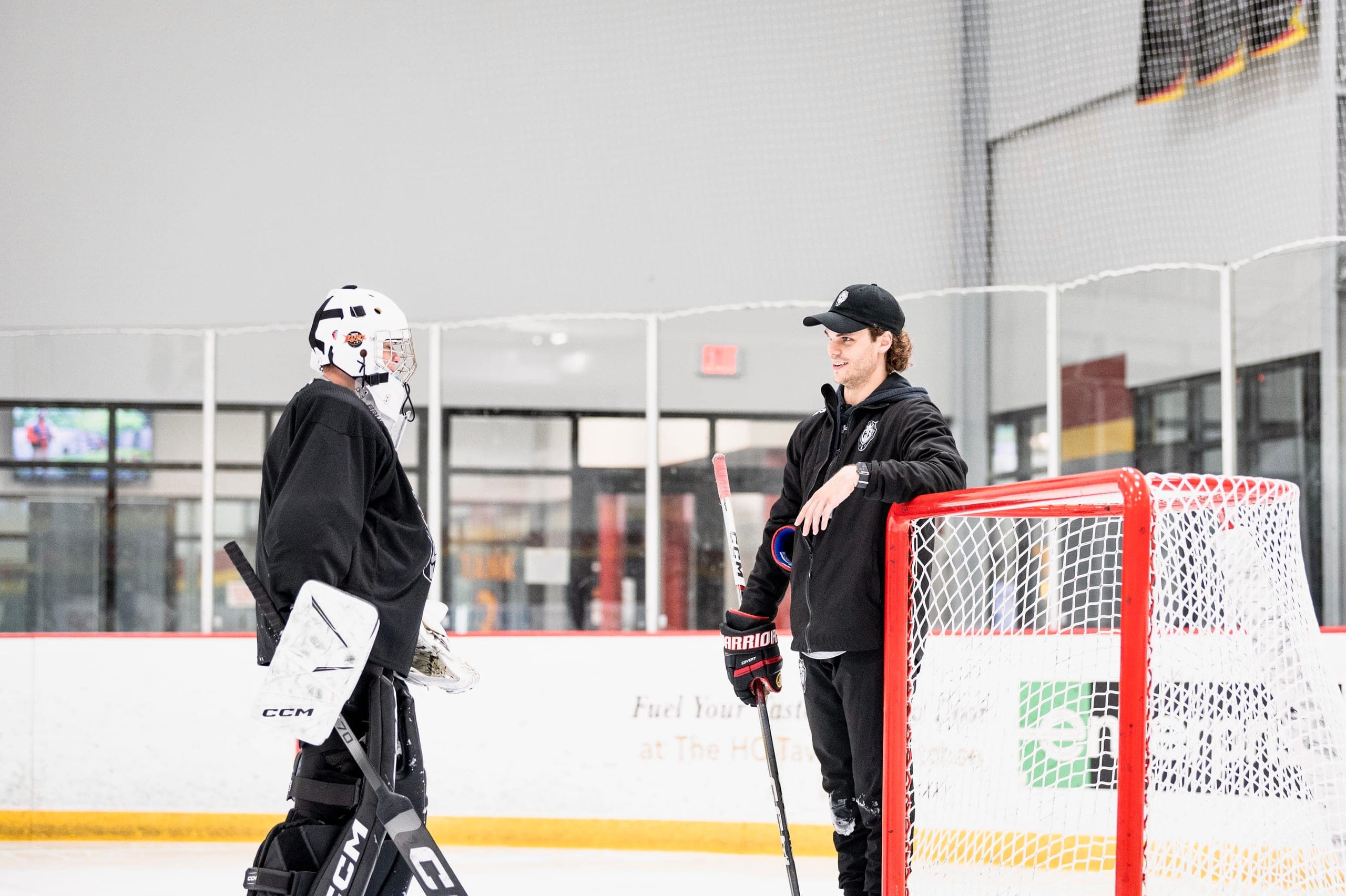 Cam Gray talking with a goalie at the net between reps.